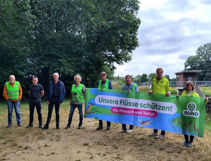 Aktion für frei fließende Flüsse an der Vechte: Die Teilnehmenden halten ein Banner